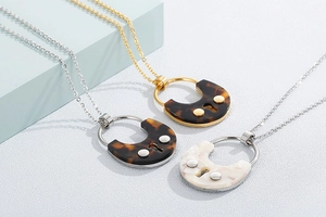 Detailed view of U-shaped tortoiseshell and mother-of-pearl pendants on fine chains