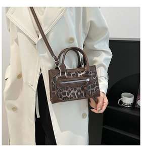 Detail of trendy leopard print handbag featuring decorative silver zippers and leather texture