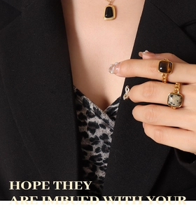 Close-up of vintage gold opal pendant necklace and square stone rings on a model