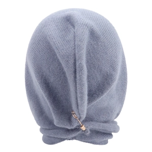 Macro detail of soft light blue knitted balaclava texture with a gold decorative pin