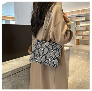 Detailed view of snake skin pattern texture on stylish crossbody bag with metal chain