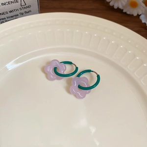 Detail view of purple frosted glass flower earrings on a textured ceramic plate