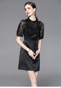Detailed view of black dress featuring intricate lace, sequins and satin fabric