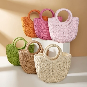 Handwoven crescent straw handbags in six vibrant colors displayed on geometric steps
