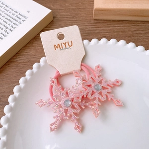 Close-up of pink glitter snowflake hair ties with rhinestones on a white ceramic plate