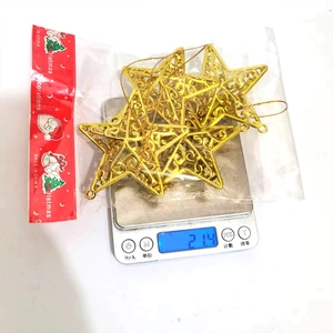 Detail showing set of 4 gold hollow Christmas star ornaments on a scale weighing 21.4g