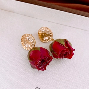 Macro shot of dark red rose bud earrings with vintage gold irregular stud detail