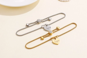 Detail of adjustable heart bracelets in gold and silver with Love charm and zircon slide