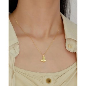 Close-up of a gold butterfly pendant necklace with radial texture on a female neck