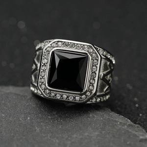 Vintage stainless steel ring with square black gemstone and diamonds on a rock background