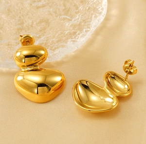 Macro shot of gold irregular oval earrings with polished finish on champagne silk texture