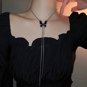 Close-up of a silver Y-shaped long necklace featuring a refined black butterfly pendant
