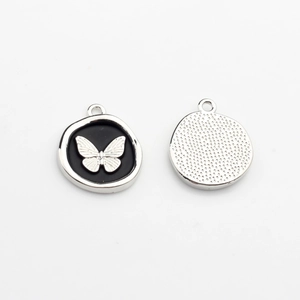 Detail view of butterfly charm pendants with black enamel and silver textured backing