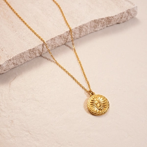 Detailed macro view of 18K gold plated sun coin pendant with embossed religious figure