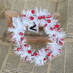 Close-up of white PVC candle ring with red snowy berries on vintage newspaper background