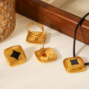 Close-up of 18K gold plated jewelry set with black enamel and textured ripple finish