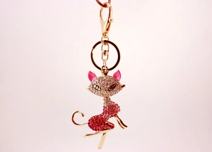 Detail of a golden cat keychain featuring pink crystals and cat eye stone ears