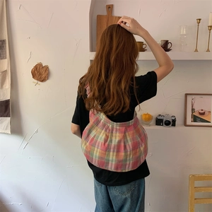 Detailed shoulder view of a pleated checkered canvas bag in pink and green patterns