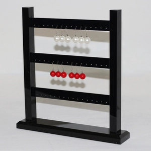 Three-tier black acrylic earring display stand with elegant pearl studs on white background