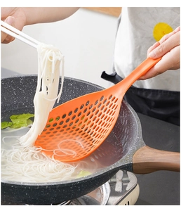Action shot of an orange long-handled strainer scooping noodles from boiling water