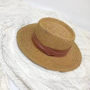 Close-up of woven straw texture and soft pink ribbon on a flat top summer sun hat