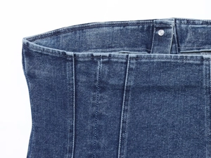 Close-up of washed blue denim tube top with silver metal button and high waist detail