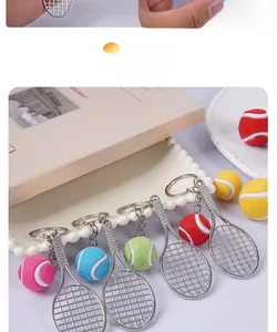 Close-up of mini tennis racket and fuzzy ball keychain on a decorative tray