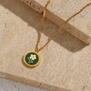 Detailed macro of 18K gold plated flower pendant on a beige natural stone background