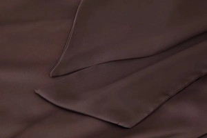Macro detail of dark brown satin dress fabric featuring precise rolled hem stitching