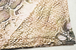 Detail of snake skin print fabric with fine stitching and earthy tone texture