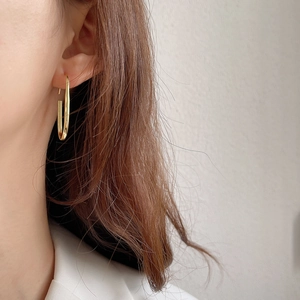 Close-up of a elegant woman wearing a polished gold U-shaped earring with minimalist style