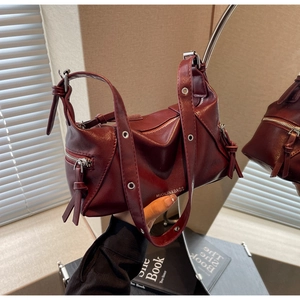 Detail view of burgundy leather tote bag with silver eyelets and branding in mirror reflection