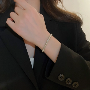 Close-up of a silver plated zircon bangle worn on wrist against a black blazer background