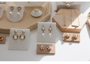 Detail showing elegant gold pearl earrings and necklaces on a marble display stand