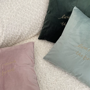 Detail of embroidered gold letters on Morandi velvet cushion covers with soft texture