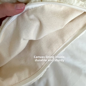 Detailed view of durable canvas lining and smooth zipper closure on creamy makeup bag