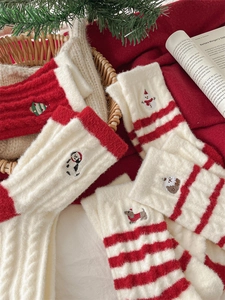 Detail of Christmas thermal socks featuring embroidered snowman and tree in a cozy gift basket