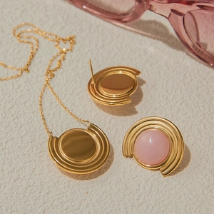 Détail du collier en titane doré et boucles d'oreilles serties de pierres roses sur pierre