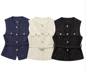 Detail of tweed vests in navy, white, and black with gold buttons and waist belts