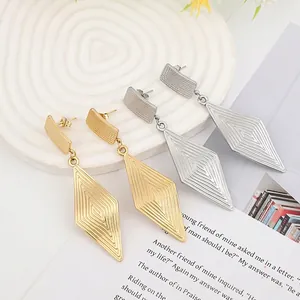 Detailed view of geometric textured gold and silver drop earrings on a stylish tray
