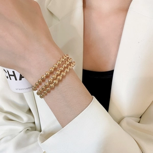 Close-up of triple layered gold beaded bracelets on wrist with polished metallic finish