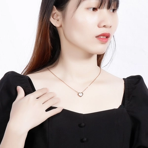 Gros plan d'un pendentif cœur en nacre sur une chaîne en acier titane couleur or rose