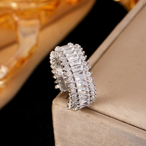 Macro shot of silver ring with baguette and round cut stones on a golden edge