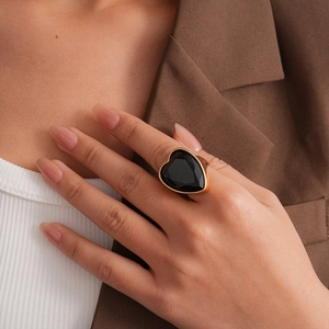 Détail d'une bague avec grande pierre noire en forme de cœur sur main et anneau doré