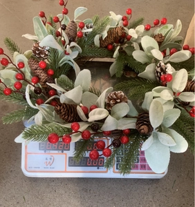 Detailed weight measurement of a Christmas wreath with red berries and pine cones