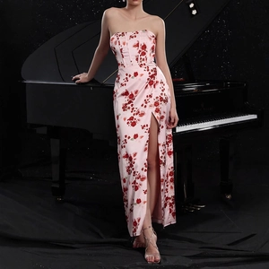 Dettaglio vestito a fiori rosa con spacco alto accanto a un pianoforte nero