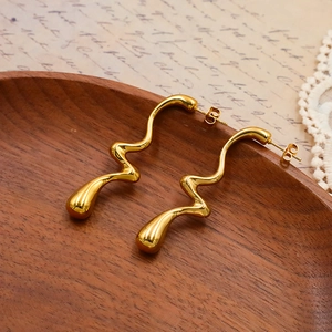 Détails de boucles d'oreilles dorées irrégulières sur un plateau en bois vintage