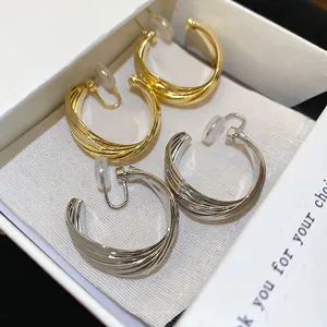 Twisted multi-layer C-shaped gold and silver clip-on earrings in jewelry box