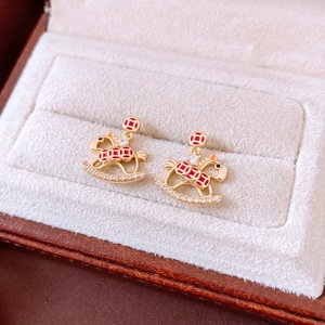 Macro shot of 18K gold-plated rocking horse stud earring with red enamel and crystals