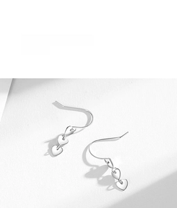Detailed view of silver triple heart-shaped pendant drop earrings with sleek ear hooks